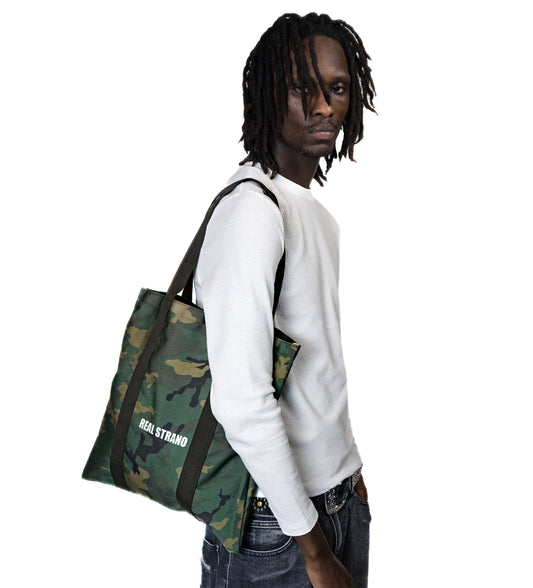 Person holding a camouflage bag on a white background